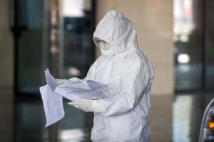 Una persona en un traje de materiales peligrosos lee un pedazo de papel