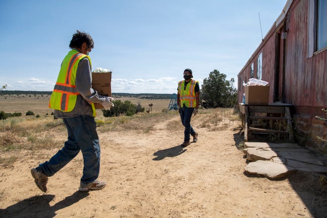 David Martine (izquierda) y Vernard Martinez (derecha) entregan suministros a la casa de Gilbert Martinez en la Reserva Indígena Ramah Navajo en Nuevo México.