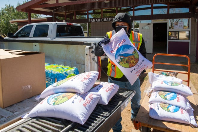 Jimmie Begay carga bolsas de harina en un camión para entregarlas a los residentes en riesgo en la Reserva Ramah Navajo en Nuevo México.  El equipo de distribución de Ramah recibe apoyo de organizaciones sin fines de lucro, como el Fondo de Ayuda COVID-19 de las familias Navajo y Hopi y McKinley Mutual Aid.